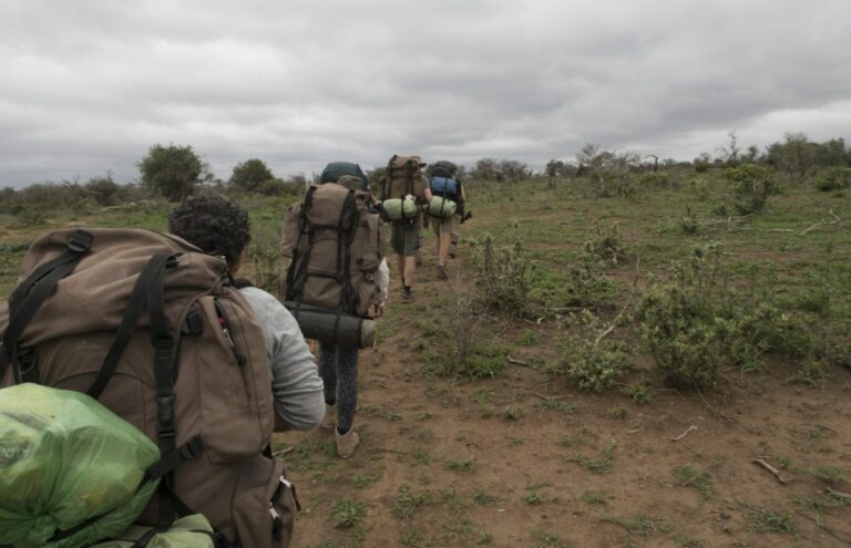 Trail groep met rugzakken lopen over een vlak pad in Imfolozi