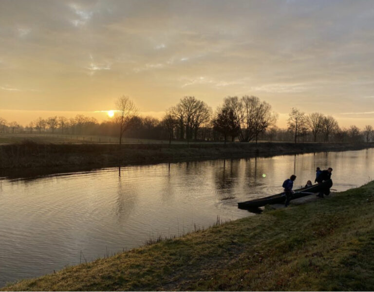 Zonsopgang boven een rivier met FNL leden die zich voorbereiden op een kano activiteit