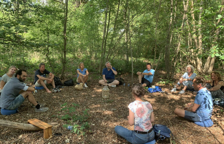 Groep deelnemers zittend in een kring in een bos tijdens een FNL evenement Jaargang Natuurlijk Leiderschap