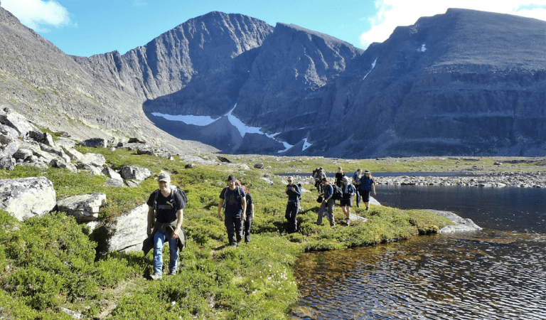 Deelnemers wandelen langs een meer omringd door heuvels tijdens een FNL trail