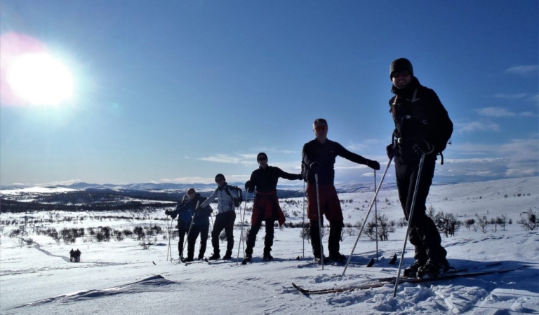 Groep trailwandelaars poseert met wandelstokken op een besneeuwde heuveltop